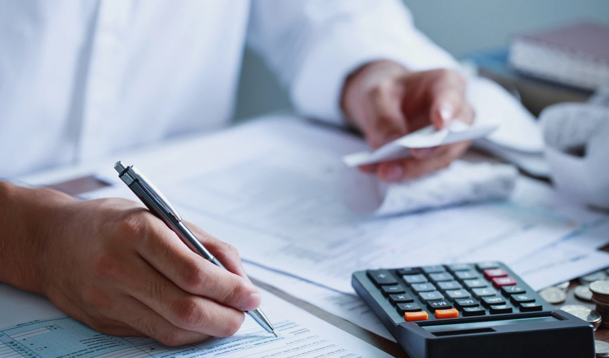 Person calculating finances with documents and calculator